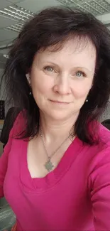 Office portrait of a woman in a bright pink shirt with natural lighting.