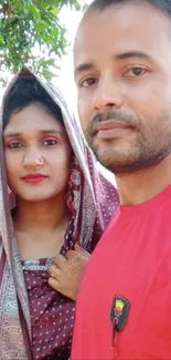 Couple in traditional attire posing outdoors, vibrant and colorful background.