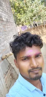 A young man with colorful face under a bright blue sky.