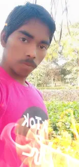 Selfie of young man in pink shirt outdoors.