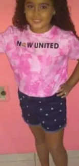 Young girl in pink tie-dye shirt with colorful backdrop.