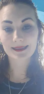 Smiling woman with curly hair against blue background.