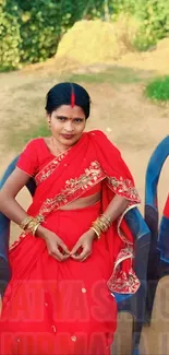 Woman in traditional red attire sitting outdoors.