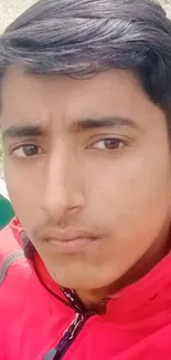 Young person takes a selfie on a park bench, wearing a bright red jacket.