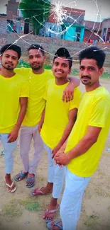 Group of friends in yellow t-shirts, standing in a rustic setting.