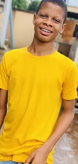 Person smiling in yellow T-shirt standing outdoors.