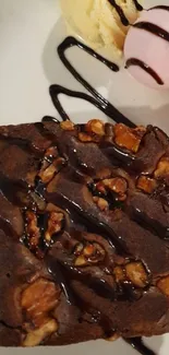 Chocolate brownie with nuts and ice cream scoops on a plate.