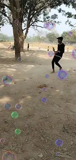 Person dancing with bubbles under trees in a natural setting.