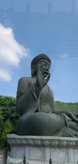 Majestic Buddha statue against a blue sky and lush green landscape.