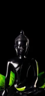 Black Buddha statue with green leaves on a dark background.