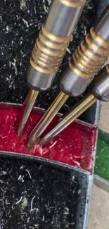 Close-up of darts hitting the bullseye on a colorful dartboard.