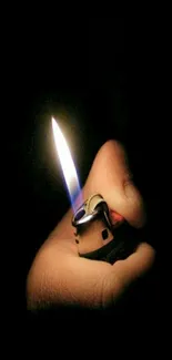 Hand holding a lighter with a bright flame against a dark background.