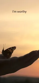 Butterfly on hand with sunset background, captioned 'I'm worthy'.