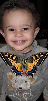 Smiling child with butterfly on sweater, creating a joyful mobile wallpaper.