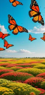 Orange butterflies over a colorful meadow under a bright blue sky.