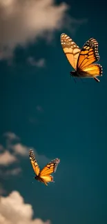 Two orange butterflies soar against a deep blue sky.