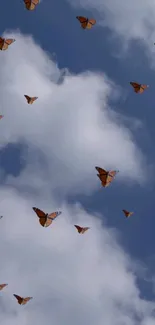 Butterflies gracefully flying in a blue sky with white clouds.