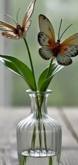 Butterflies on green leaves in a glass vase.