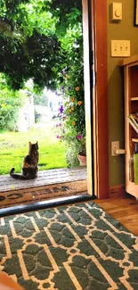 Cat sitting by an open door with a garden view.