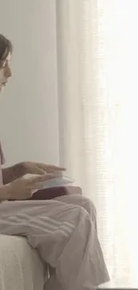 Woman reading in a sunlit room with soft beige tones.