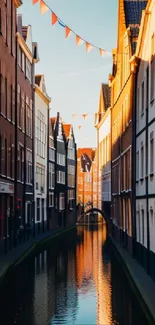 Canal street with hanging flags at sunset, reflecting orange hues.