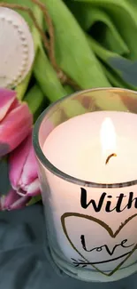 Candle with heart design and pink tulips on green background.