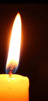 A glowing candle flame with a dark background for mobile wallpaper.