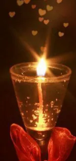 Candle in a glass with glowing hearts, casting a warm ambiance.