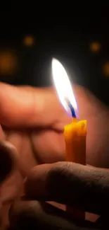 Hands holding a glowing candle in darkness.