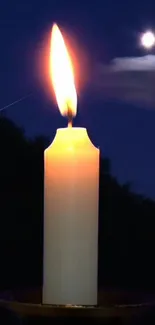 Candle glowing under a serene night sky with a visible moon.