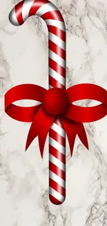 Red candy cane with ribbon on marble wallpaper.