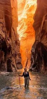 Person exploring a sunlit canyon with vivid orange rock walls.