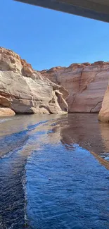 Canyon walls reflecting in a calm waterway under a clear blue sky.