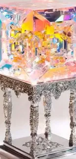 Ornate crystal cube on silver stand, vibrant hues.