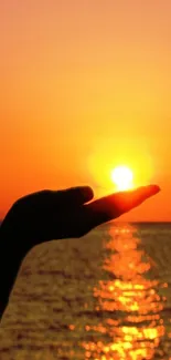 Beautiful orange sunset over ocean with hand silhouette.