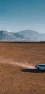 Car driving in wide desert landscape with mountains.