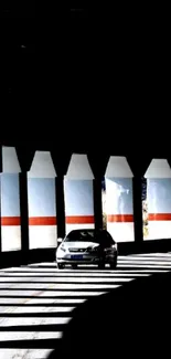 Car driving through a shadowed tunnel with dramatic lighting.