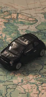 Black toy car on a teal map wallpaper.