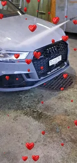 Gray car with red hearts design in a garage setting.