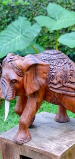 Intricate wooden elephant sculpture in a lush natural setting on a rustic platform.