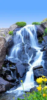 Beautiful waterfall with blue sky and vibrant flowers.