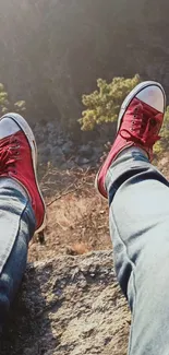 Red sneakers overlooking a cliff edge with blue jeans.