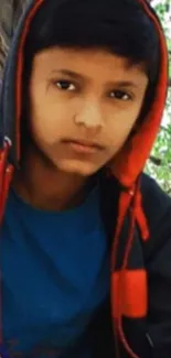 Portrait of a young person in a red and black hoodie outdoors.