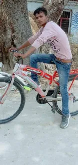 Young man on a bicycle in a casual setting with a natural backdrop.