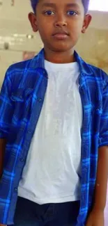 Young boy in a blue checkered shirt standing indoors.