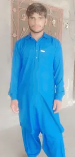 Person wearing blue traditional outfit standing indoors.