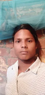 Person in front of a brick wall with blue fabric on top.