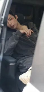 Person in dark attire relaxing in car seat.