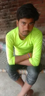 Young man in a neon green shirt sitting casually on a woven chair.