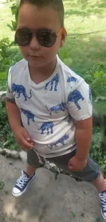 Child in sunglasses posing outdoors with playful style.